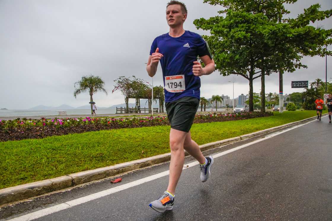 Uma foto minha correndo na Meia-maratona internacional de Floripa em 2021 com o mar ao fundo.